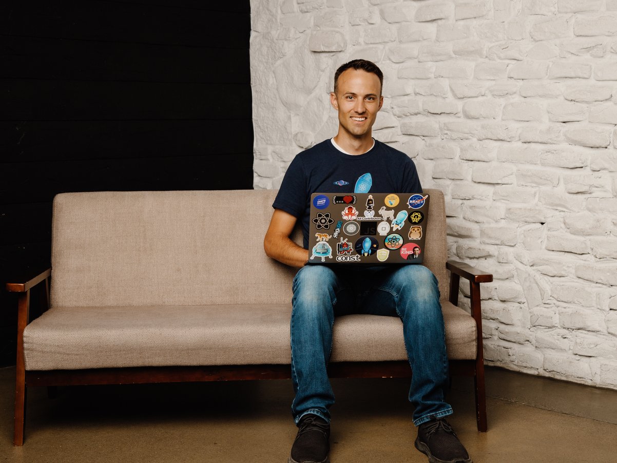 Kent smiling with laptop on a couch