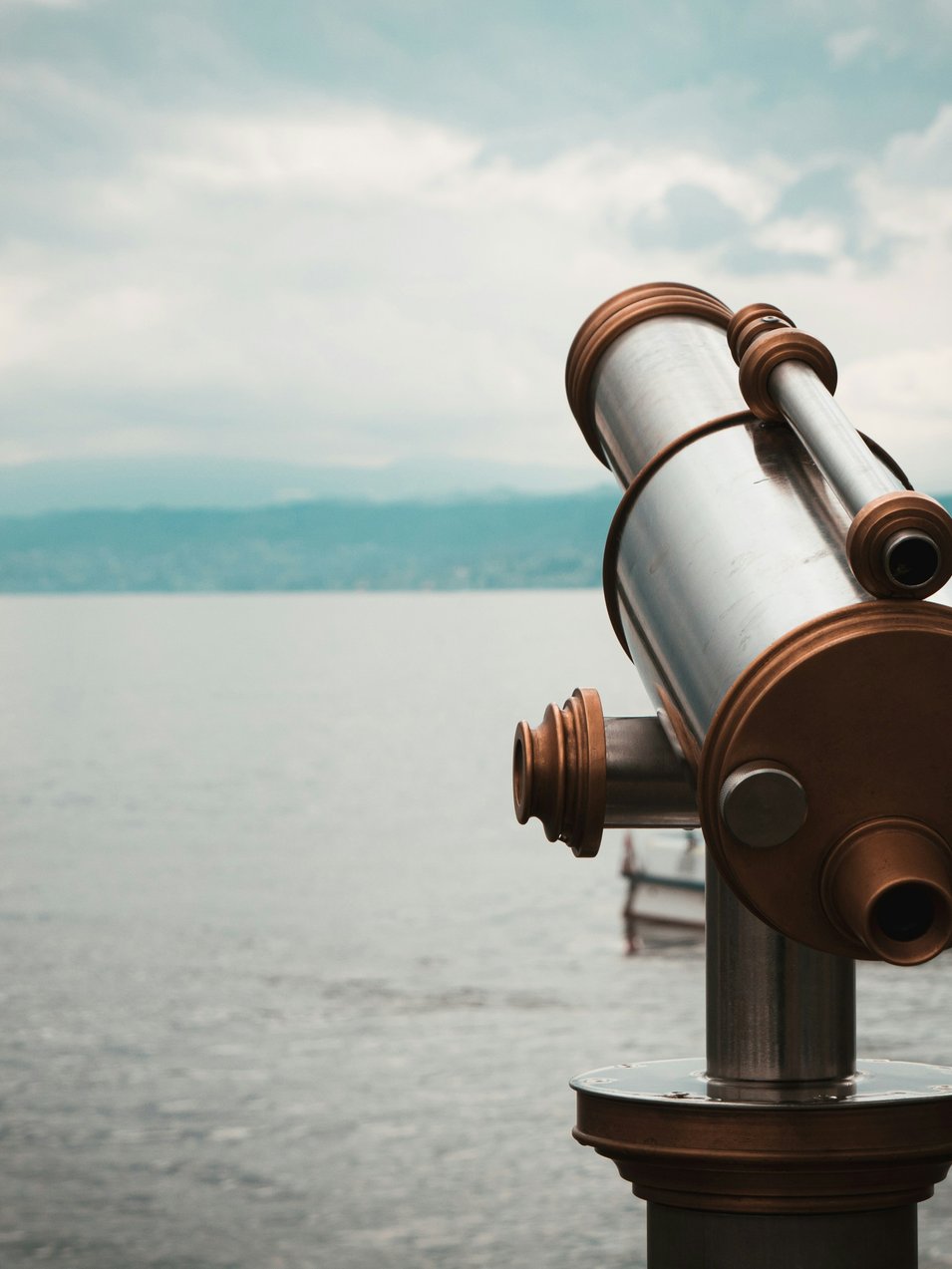Brown and silver telescope near body of water during daytime