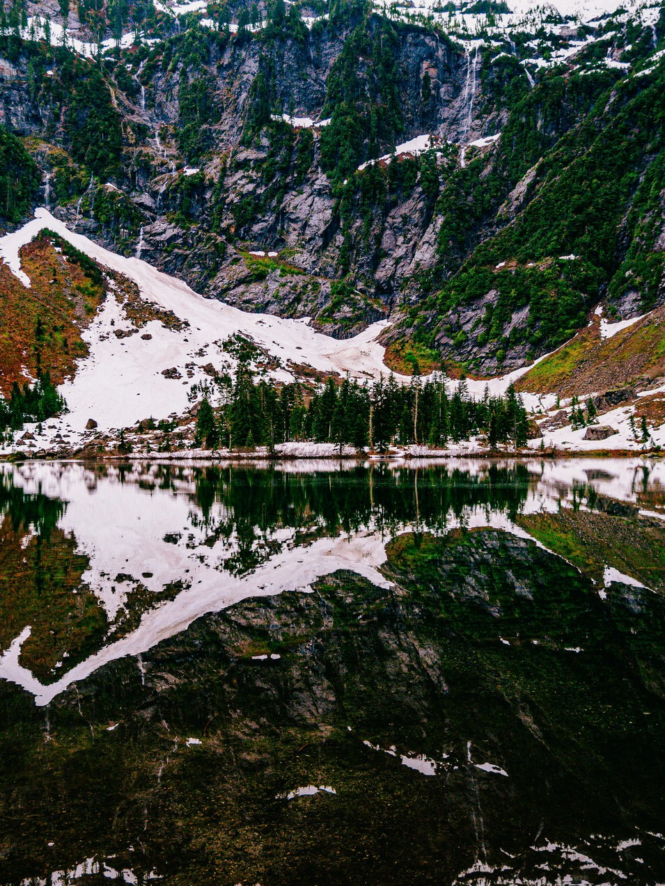 A mountain range with a lake surrounded by snow